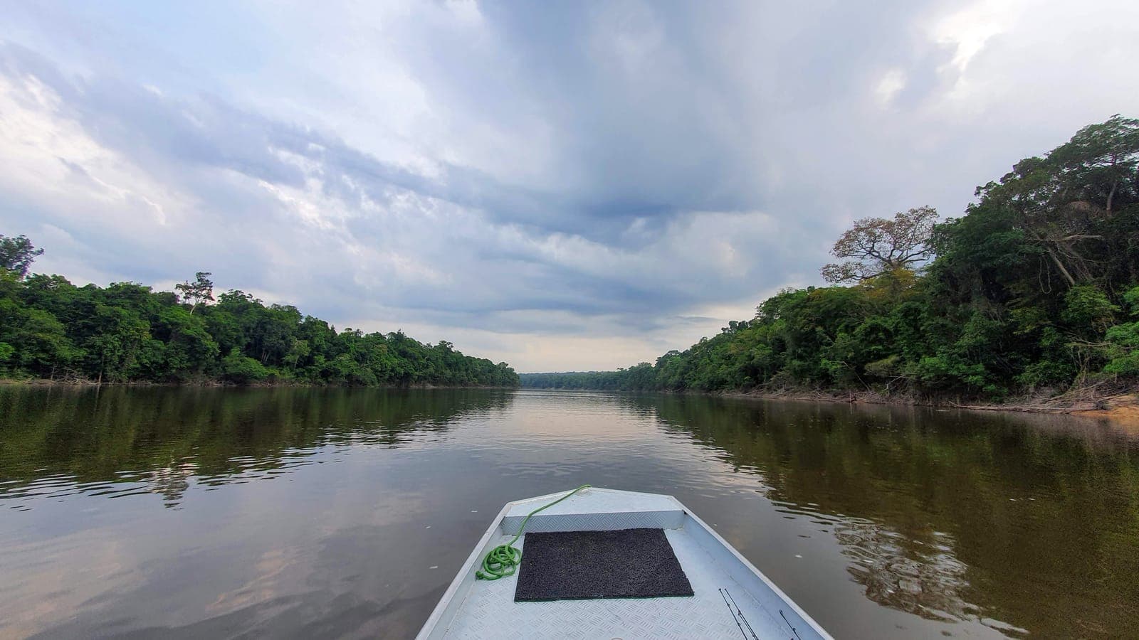 Barco descendo um rio amazônico ao amanhecer