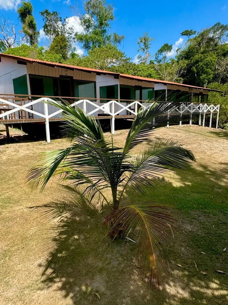 Main facade of Pousada Acari with front porch, red roof and garden in the Amazon