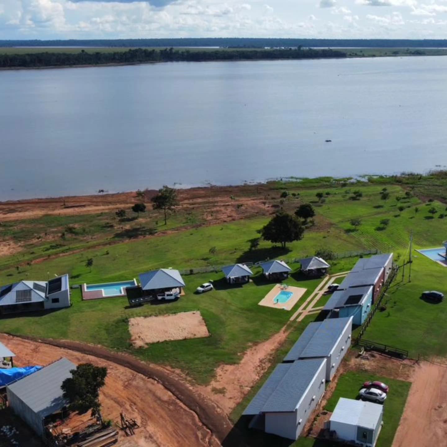 Aerial view of Pousada Adventure showing two rows of chalets, pools and lawn on the Teles Pires riverbank in Sinop, MT.